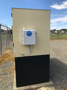 Outdoor equipment cabinet with a small white communications box mounted on the side.