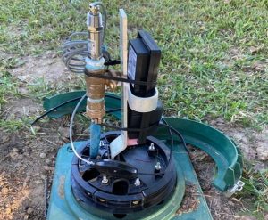 Sensor and piping assembly inside an open green underground utility box.